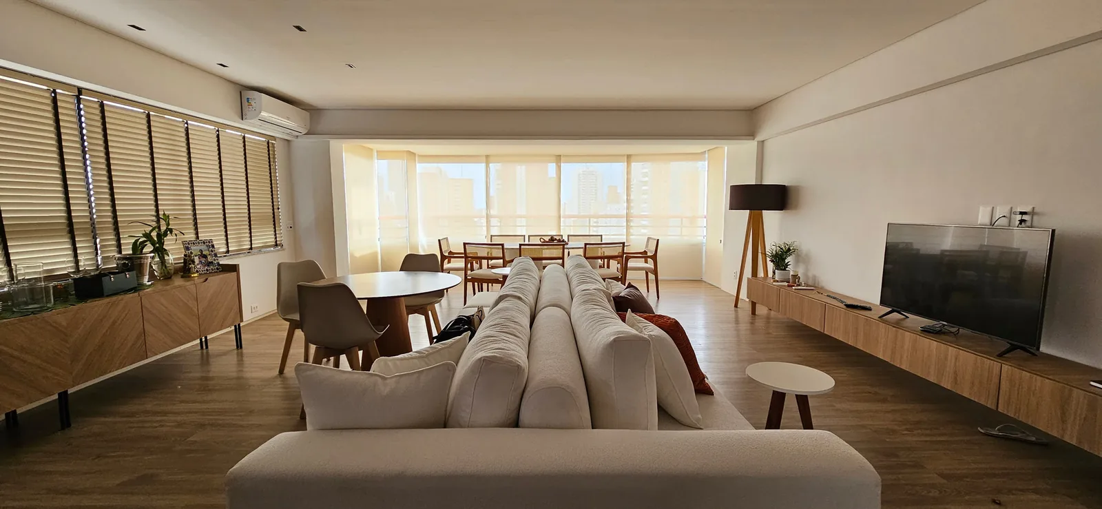 Sala com cortinas de linho e persiana rolô instaladas pela Inário